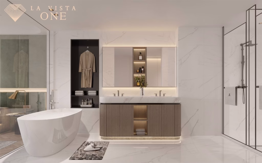 A modern luxury penthouse bathroom featuring a freestanding bathtub, double sink vanity with wood cabinets, illuminated mirrors, open shelves, walk-in shower, and a robe in an alcove—all set against marble walls and floors.