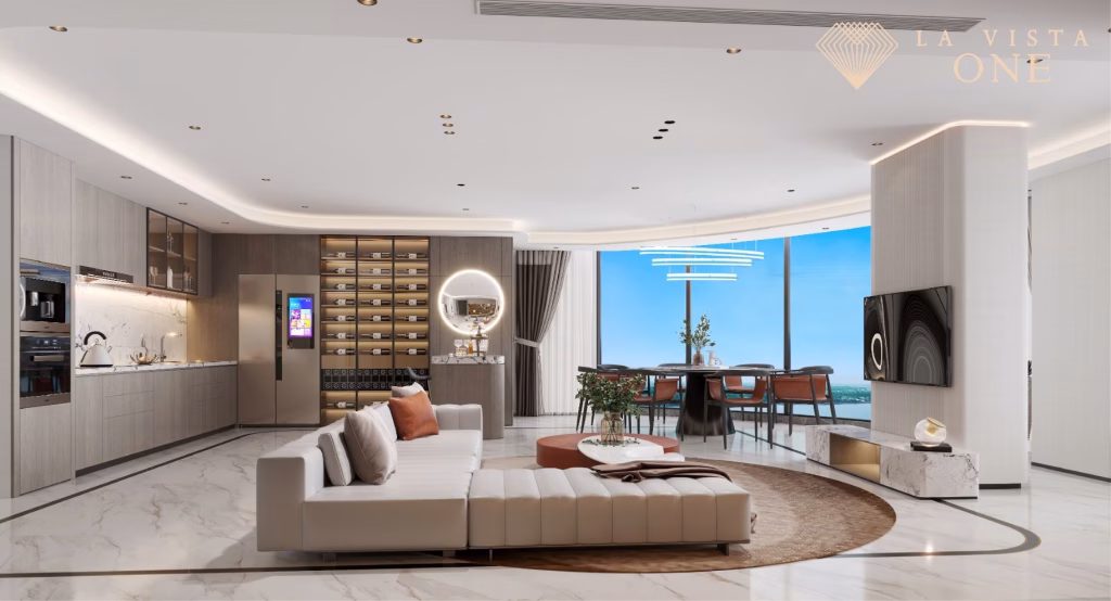 Modern open-plan living and dining area in this luxury penthouse features marble floors, neutral tones, a sectional sofa, large windows with city views, built-in kitchen appliances, and elegant lighting. La Vista One logo appears in the top right corner.