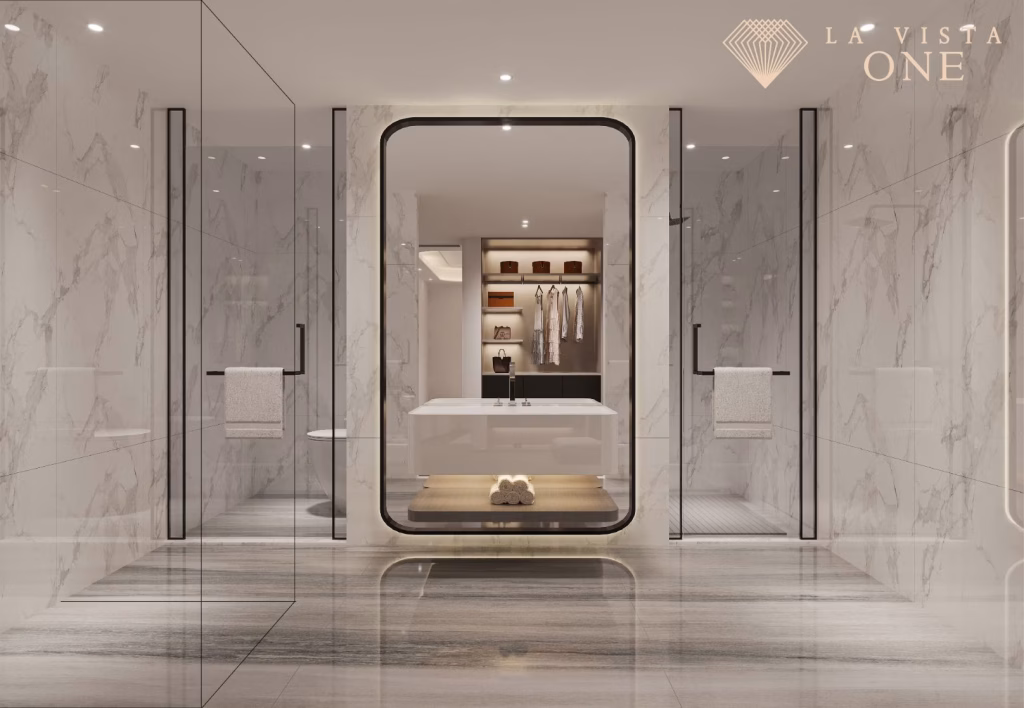 A luxurious, modern bathroom at La Vista One features marble walls and floors, glass shower enclosures on each side, a central bathtub, and an open closet with neatly arranged clothes. LA VISTA ONE logo sits in the top right corner.