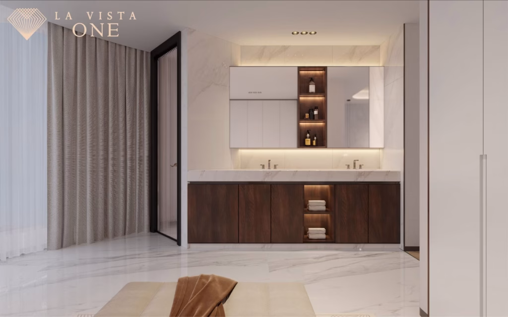 Modern Riverside Penthouse bathroom with marble floors, a double sink vanity featuring dark wood and white cabinets, open shelves with decor and towels, soft lighting, floor-to-ceiling curtains. La Vista One logo in the top left corner.