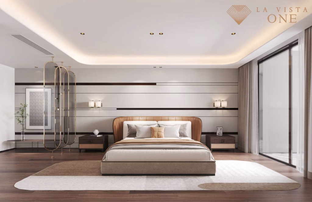 A modern, spacious bedroom at La Vista One with a large bed, elegant lighting, wooden floors, and minimalist decor. Natural light streams through a floor-to-ceiling window. The wall features horizontal lines and the La Vista One logo in the top right corner.