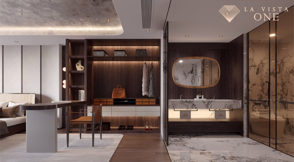 A modern, luxurious La Vista One hotel suite with a workspace, wooden shelves, a vanity area with a large mirror, marble countertops, glass shower, and warm ambient lighting. The “La Vista One” logo is in the top right corner.