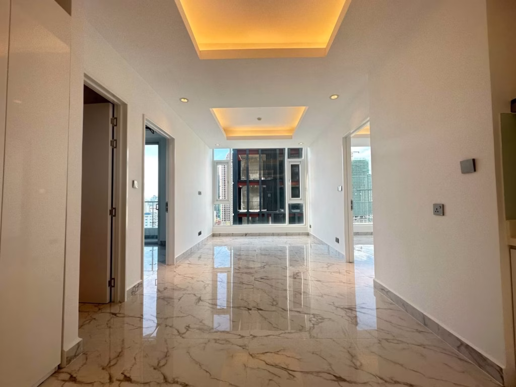 A modern, unfurnished 2 bedroom apartment with glossy marble floors, white walls, recessed ceiling lights, and large windows offering a city view. Two open doorways lead to other rooms.