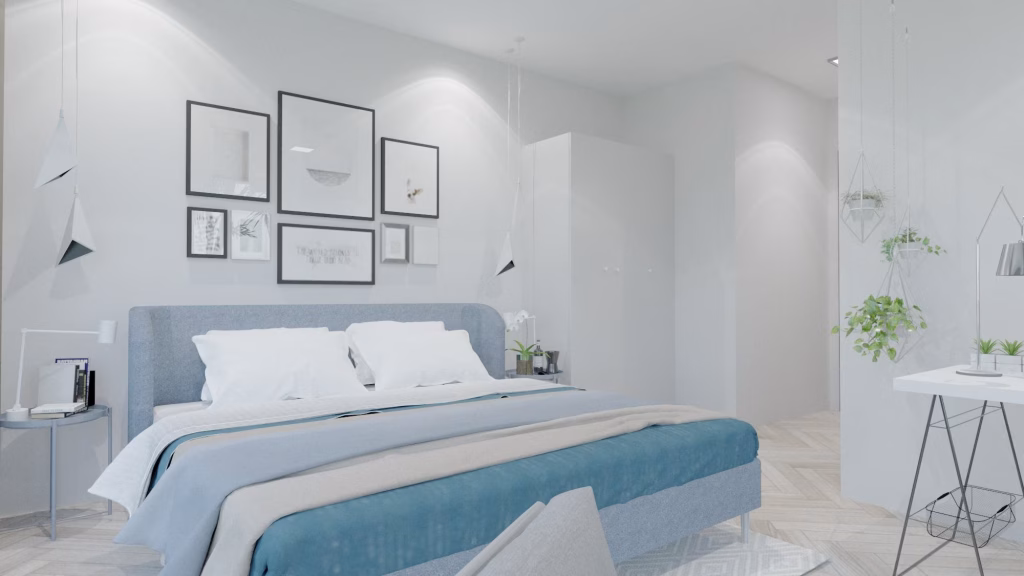 A modern, minimalist bedroom at Oasis Harmony villas features a grey bed, white bedding, and blue accents. Framed art adorns the wall above, while nightstands with books and plants pair perfectly with hanging planters for a touch of greenery.