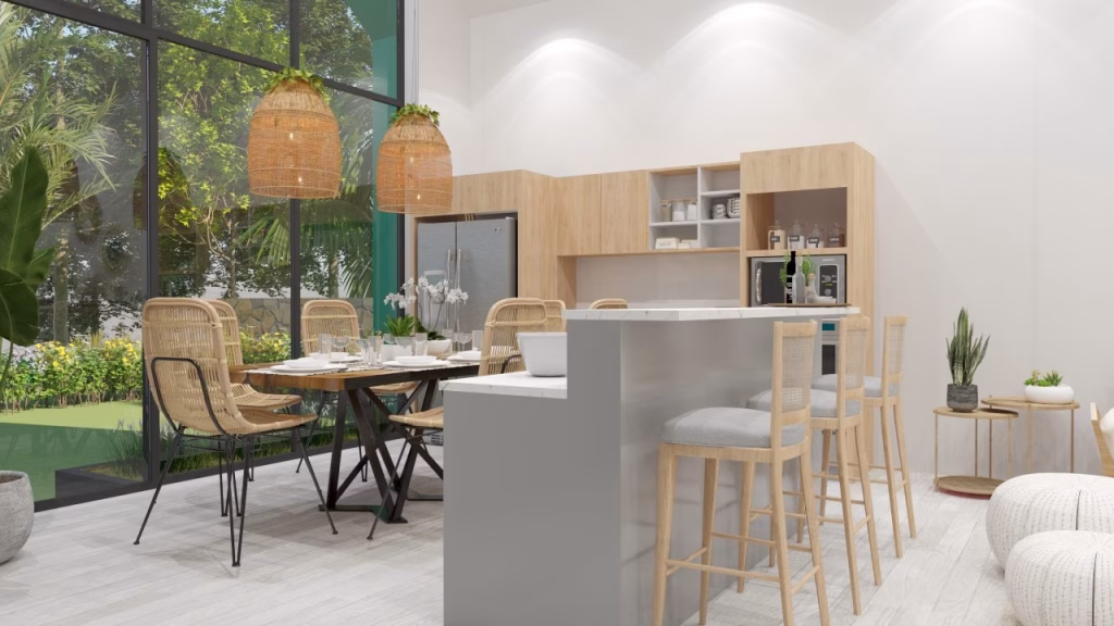 Modern kitchen and dining area with wooden furniture, wicker chairs, bar stools, pendant lights, and large windows overlooking greenery—ideal for those seeking Kampot homes for sale. Bright and airy space with neutral tones and indoor plants.
