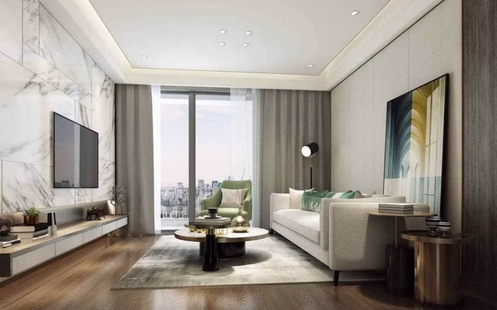 Modern living room with a white sofa, abstract wall art, and accent chair by a large window offering city views—ideal for those seeking a Sihanoukville Studio For Sale. Neutral tones, wood flooring, and marble panels add stylish elegance.