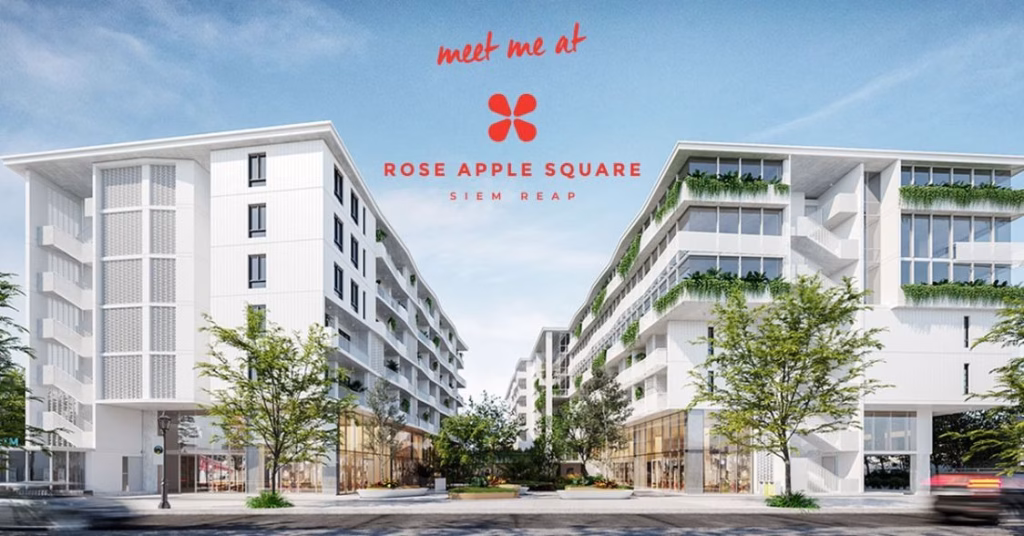 A modern plaza with two white multi-story buildings featuring greenery on balconies, trees along the street, and clear blue skies. Meet me at Rose Apple Square Siem Reap appears above with a red flower logo.