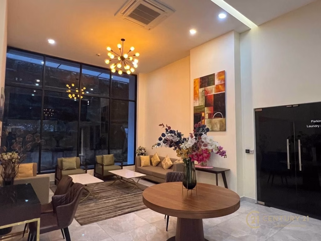 Modern lobby with large windows, cozy seating area, decorative lighting, and marble flooring—perfect for those seeking a studio apartment for rent. A glass door with Century 21 branding is visible on the right.