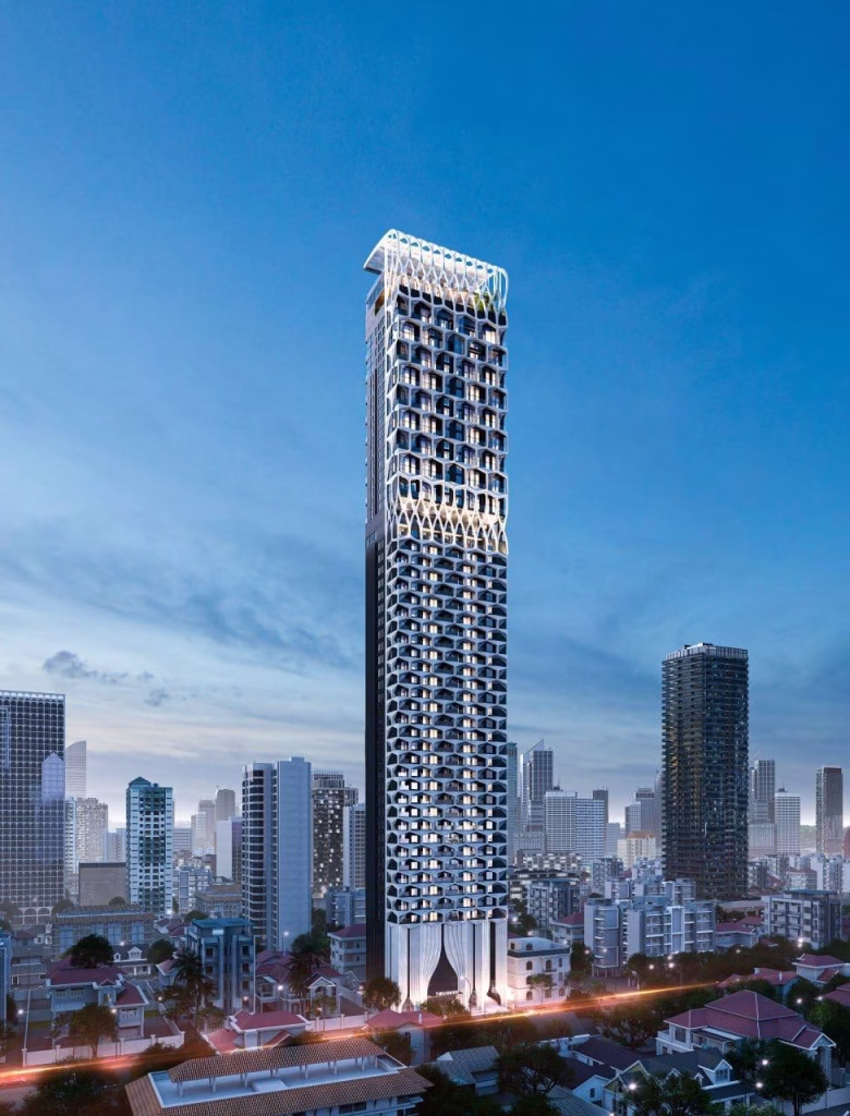A modern, tall skyscraper with a unique geometric facade stands prominently among shorter buildings and high-rises in the Time Square 6 cityscape at dusk, set against a blue sky and illuminated by vibrant city lights below.