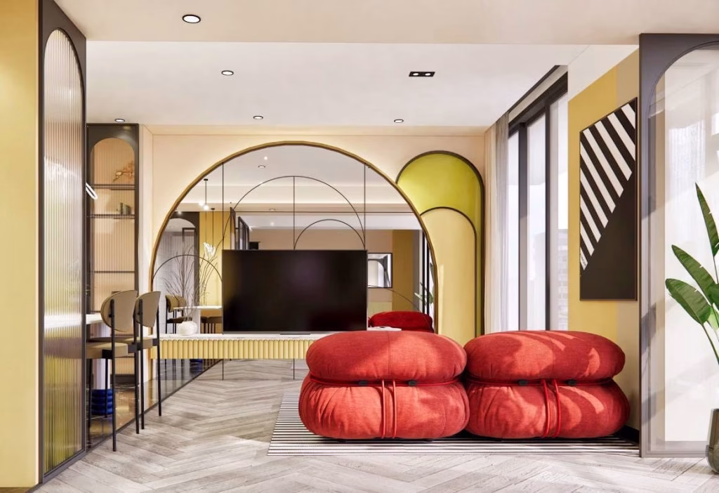 Modern living room with bright yellow walls, two large red cushioned seats, a black TV on a stand, geometric decor, and large windows bringing in natural light—like your own Time Square 6 retreat. Light wood herringbone floors and a corner plant complete the look.
