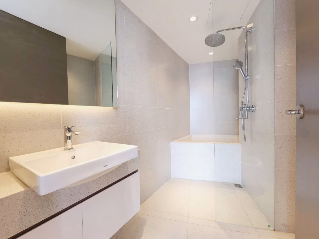 Modern bathroom in a 1 bedroom condo with a large white sink, wall-mounted faucet, and a spacious walk-in shower featuring a rainfall showerhead, glass divider, and light gray tiled walls and floors.