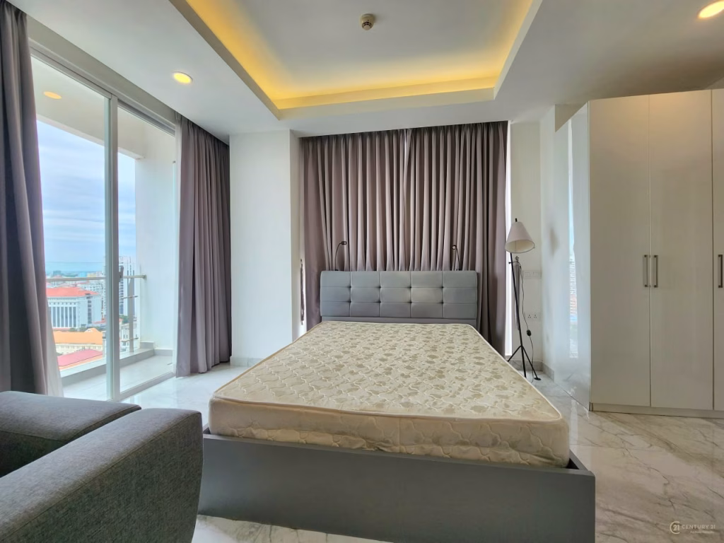 A modern condo for sale featuring a spacious bedroom with a large window, gray curtains, a gray upholstered bed without bedding, standing lamp, white wardrobe, and marble floors. Natural light fills the room with stunning city views.