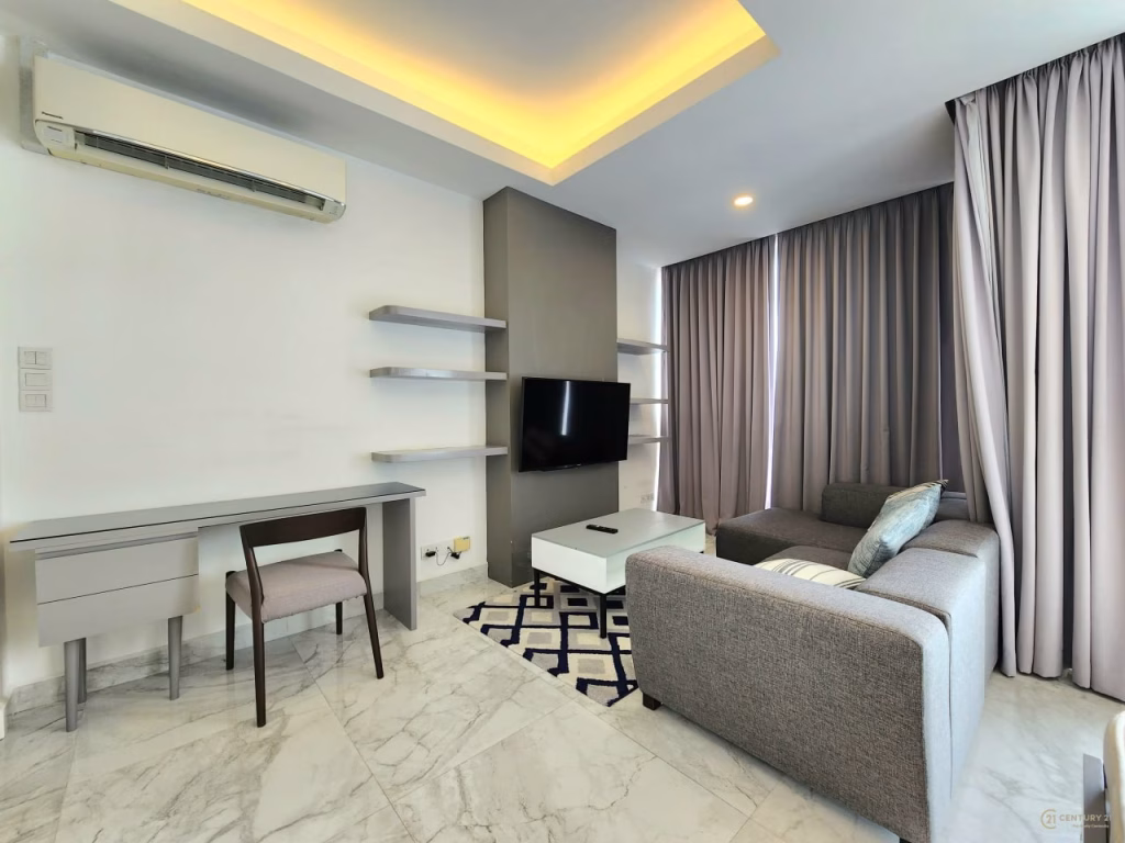 A modern condo for sale featuring a gray sofa, white coffee table, wall-mounted TV, desk with chair, and built-in shelves. Enjoy marble flooring, floor-to-ceiling curtains, and recessed ceiling lighting in this stunning living room.