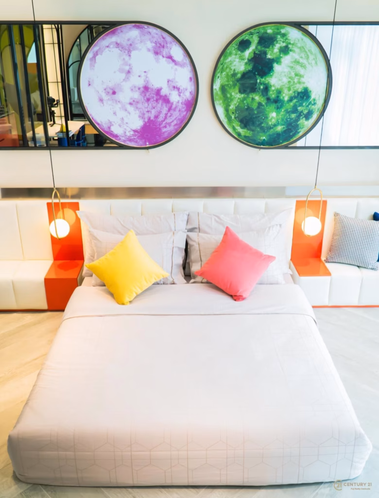 A modern bedroom with a neatly made bed, pastel pillows, two pendant lights, and two large moon-themed artworks above the headboard—perfectly reflecting the contemporary style of the Time Square 6 Project.